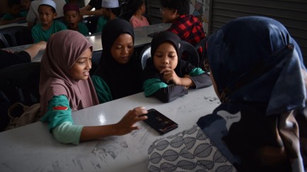 Children learning bead crafting in a classroom